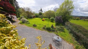A garden with a gravel path, a table with chairs, and a wooden chair.