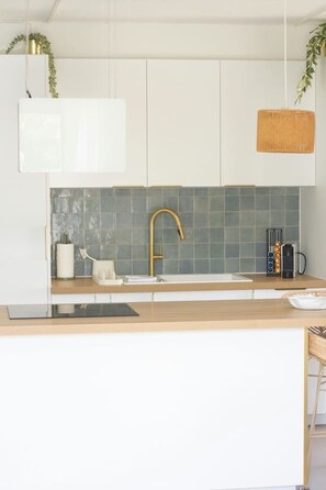 Eine moderne Küche mit einer Holzarbeitsplatte, einem goldenen Wasserhahn und einer gefliesten Spritzschutzwand.