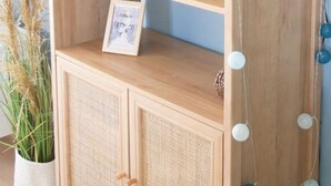 Una estantería de madera con un cuadro enmarco, un altavoz pequeño y objetos decorativos.