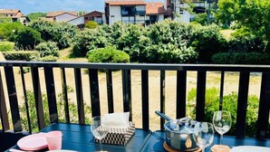 Mesa de comedor al aire libre con platos, cubiertos y vasos, rodeada por una barandilla negra.