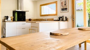 Una cocina moderna con una mesa de madera, luces colgantes y un amplio ventanal.