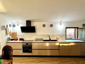 Eine moderne Küche mit Einbauofen, Mikrowelle, Spüle und einem Fenster mit Blick ins Freie.
