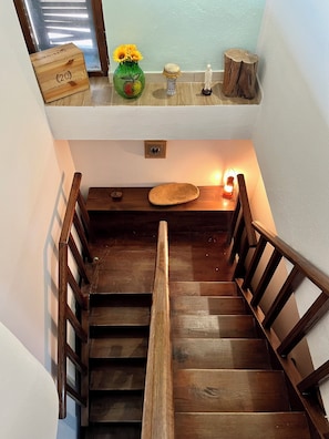 Eine Holztreppe mit Handlauf, ein kleiner Tisch mit Blumenvase und eine Holzschatulle auf der Zwischenebene.