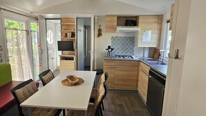 Une cuisine compacte avec un coin repas, un téléviseur intégré et une vue à travers la porte coulissante.