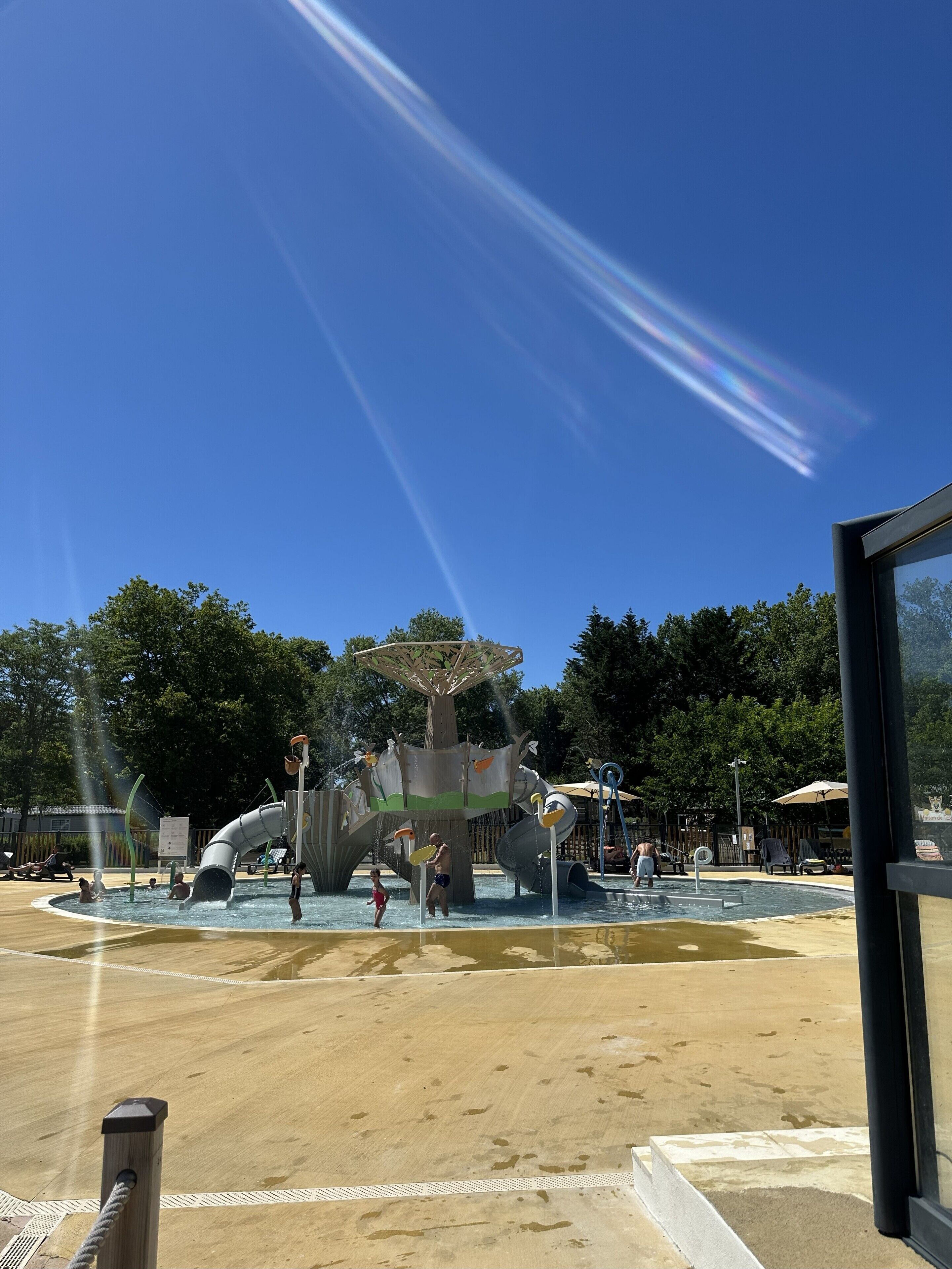 A water park with a large slide structure, a pool, and a sandy area.