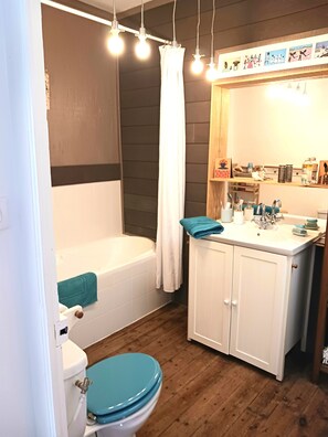 Ein Badezimmer mit Badewanne, Toilette, Waschbecken und Spiegel.