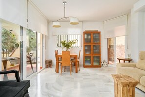 A spacious living area with a dining table, chairs, a sofa, and a wooden cabinet. - Casa Mamá: Sea Views, Private Pool & Wi-Fi on the Costa Tropical (Almuñécar)
