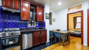 A kitchen with wooden cabinets, a gas stove, an oven, and a dishwasher. - Enjoy Easy Access to the West side Manhattan (New York)