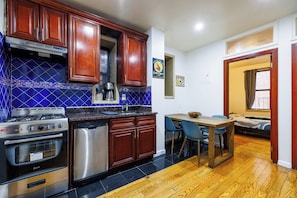 A kitchen with wooden cabinets, a gas stove, an oven, and a dishwasher. - Enjoy Easy Access to the West side Manhattan (New York)