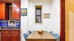 A kitchen with wooden cabinets and a blue tiled backsplash, a dining table with chairs, and a window with a view. - Enjoy Easy Access to the West side Manhattan (New York)