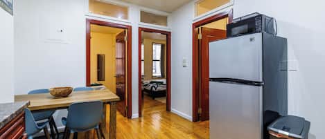 A kitchen with a refrigerator, microwave, and dining area with chairs and a table.