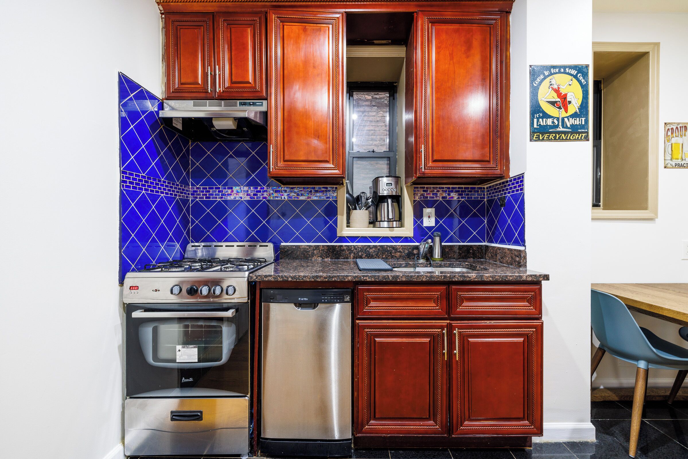 A kitchen with wooden cabinets, a stove, a dishwasher, and blue-tiled backsplash.