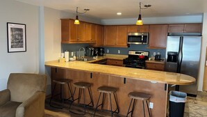 Una cocina moderna con armarios de madera, un refrigerador de acero inoxidable, un microondas y una cafetera.