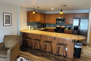 A modern kitchen with wooden cabinets, a stainless steel refrigerator, a microwave, and a coffee maker. - Convenience and Amenities in the Resort Base (Taos Ski Valley)