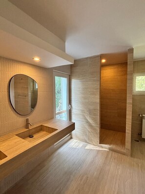 Een moderne badkamer met een grote spiegel, een houten wastafelmeubel en een douchehoek.