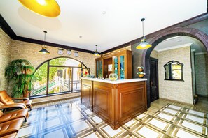 A spacious lobby with a large wooden reception desk, a seating area with leather chairs, and a view of a bridge through the glass doors. - Quba Qala Resort (Quba)