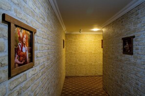Un pasillo con paredes de ladrillo y suelo estampado, que conduce a una habitación con un cuadro en la pared.
