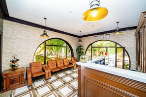 Un hall de hotel con zona de estar, una recepción y vistas a través de ventanales abovedados.