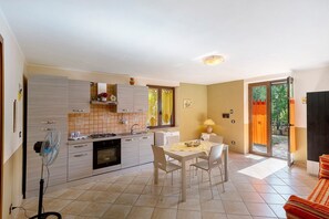 A modern kitchen with a dining area, a fan, and a view of the outdoors. - La Grande Quercia, relaxation in the heart of Cilento (Perdifumo)