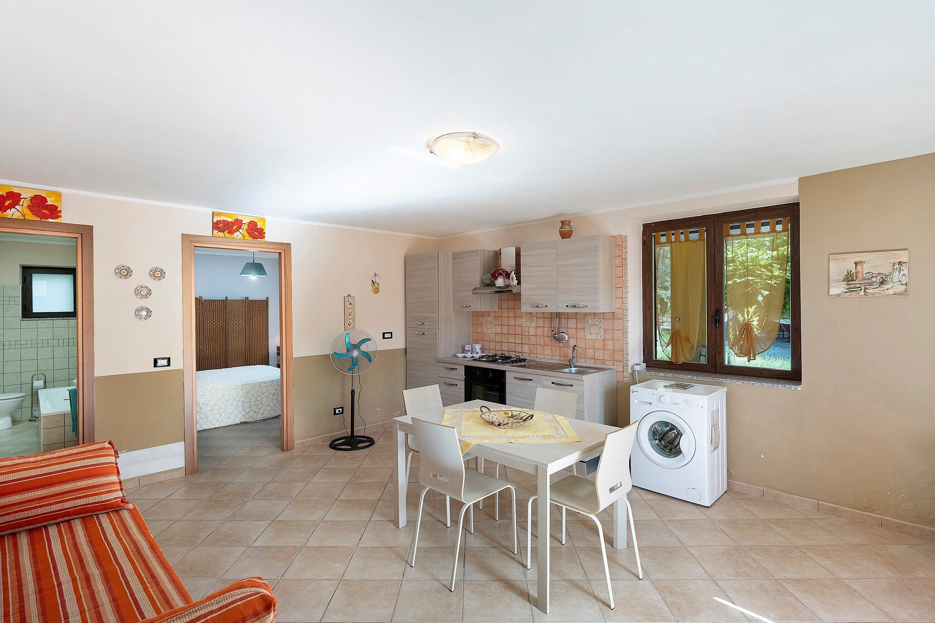 Un espace de vie compact comprenant un coin repas, une cuisine et un lave-linge.