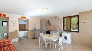 Un ambiente compatto con angolo ristoro, cucina e lavatrice.