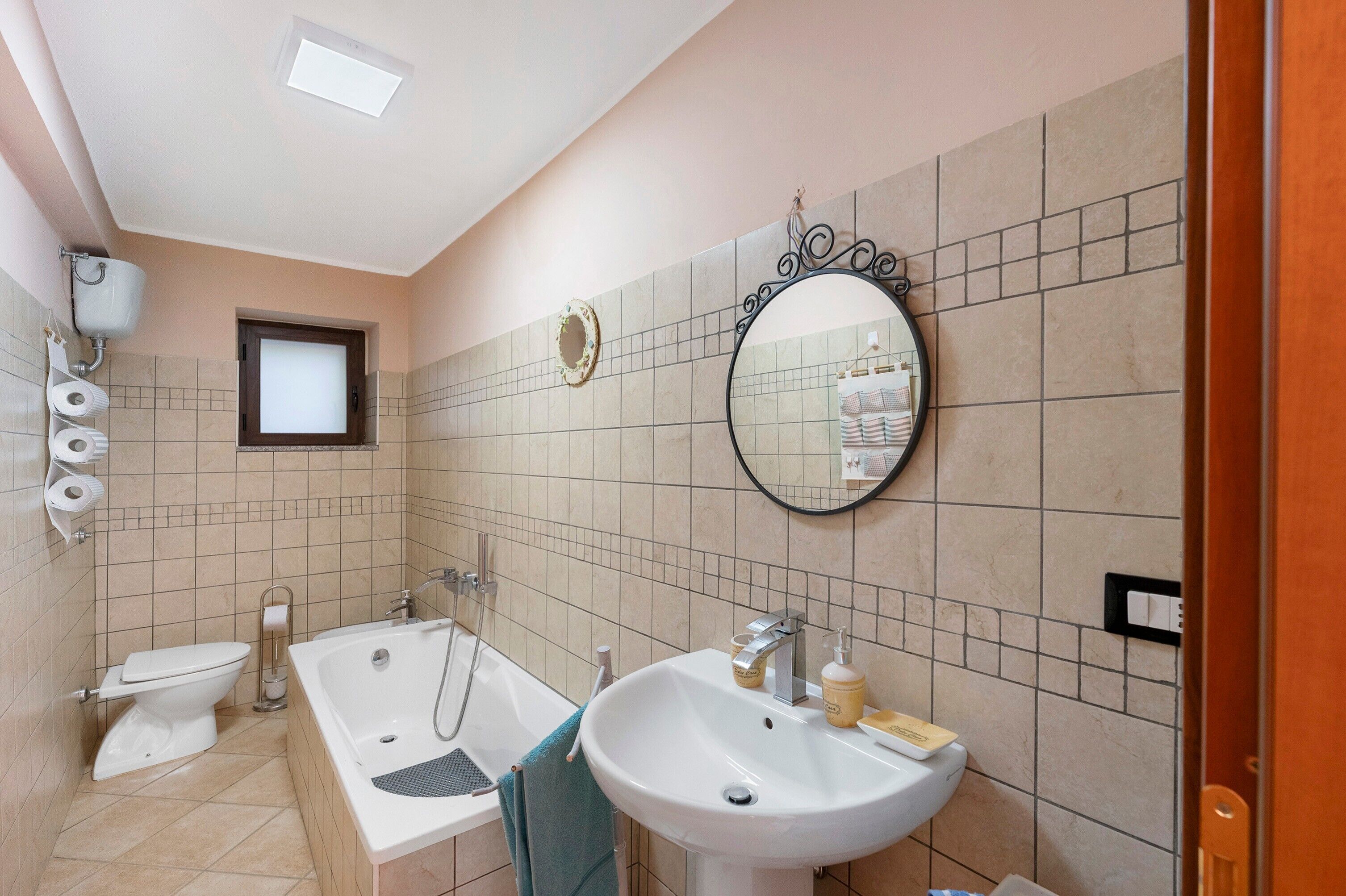 Un bagno con vasca, lavandino, wc e specchio.