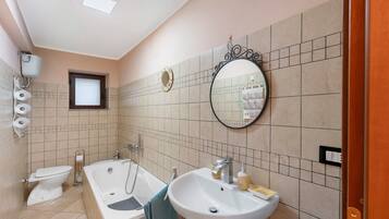 Un bagno con vasca, lavandino, wc e specchio.