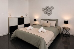 A modern bedroom with a bed, bedside tables, and wall art. - Villa Magali – Swimming pool, golf and beach (Charneca de Caparica)
