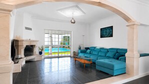 Un salón amplio con un sofá azul, una chimenea y vistas a una piscina.