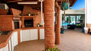 Una cocina de ladrillo con horno empotrado, armarios blancos y plantas colgantes.