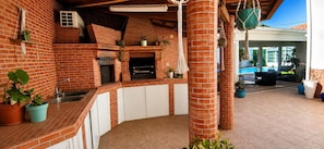 A brick kitchen with a built-in oven, white cabinets, and hanging plants. - Villa Magali – Swimming pool, golf and beach (Charneca de Caparica)