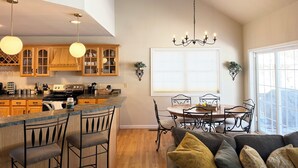 A modern kitchen with wooden cabinets, a bar area, and a dining set. - Perfect Pocono Retreat / Golf / FirePit /Swimming Pool/BBQ near Waterparks (Tobyhanna)