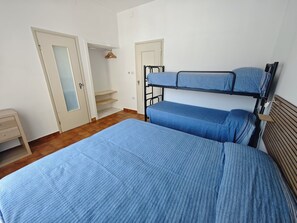Ein Zimmer mit einem Etagenbett, einem Holznachttisch, einer Tür mit Spiegel und Holzboden.