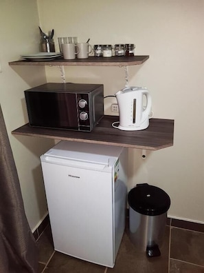 A compact kitchenette with a microwave, toaster, and small refrigerator.