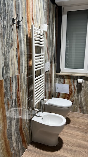 Ein Badezimmer mit zwei Toiletten, einem weißen Waschbecken, einem Handtuchhalter und einem Toilettenpapierrollenhalter.