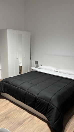 Ein Schlafzimmer mit einem Bett, einem Nachttisch, einer Lampe und einem Kleiderschrank.