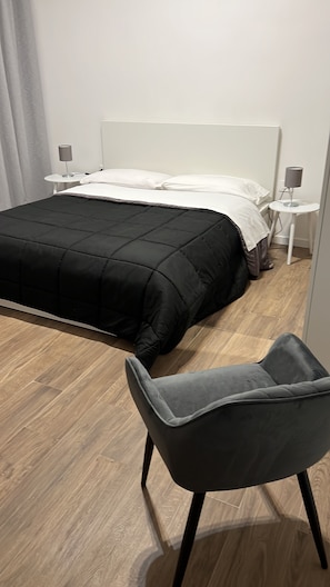Ein modernes Schlafzimmer mit Bett, Nachttisch, Sessel und Lampe.