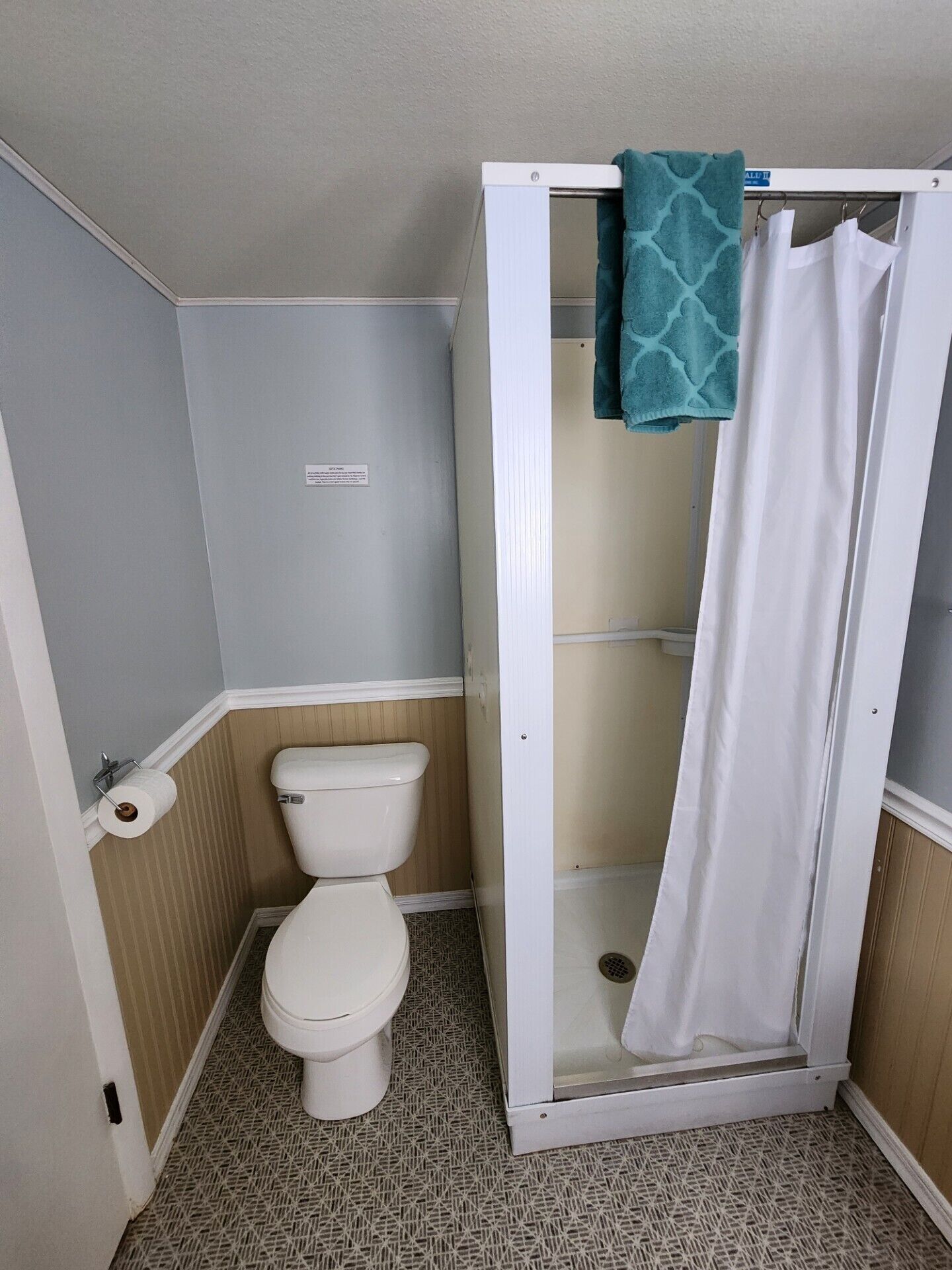 A bathroom with a toilet, a shower enclosure, and a towel rack.
