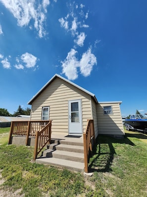 A small, single-story house with a front porch and a set of stairs leading to the door.