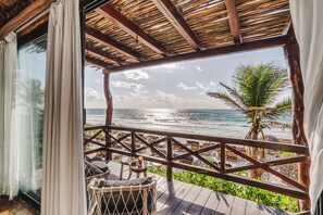 Une terrasse en bois offrant une vue sur lâocĂ©an, avec un palmier et une plage.