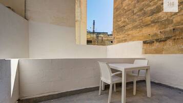 A small outdoor seating area with a table and chairs, a brick wall, and a sign indicating '360 ESTATES'.