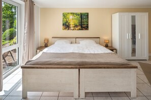 Un letto matrimoniale con testiera in legno, due comodini con lampade, un armadio e un'ampia finestra con tende.
