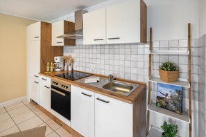 Eine moderne Küche mit weißen Schränken, einer Holz Arbeitsplatte, einem eingebauten Herd und einem Spülbecken.