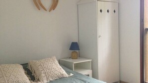 Ett sovrum med en säng, kuddar, en lampa, en garderob och en väggdekoration.