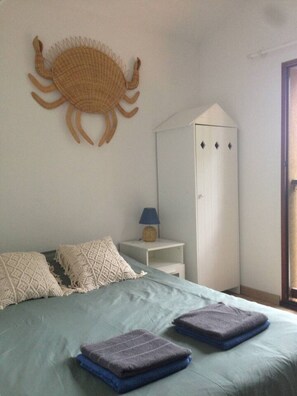 Ein Schlafzimmer mit Bett, Kissen, einer Lampe, einem Kleiderschrank und einer Wanddekoration.
