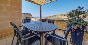 Ein runder Tisch mit vier Stühlen, ein Grill und ein Blumentopf auf einem Balkon mit Blick auf die Landschaft.