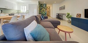 Ein modernes Wohnzimmer mit einer Eckcouch, einem Essbereich und einer Küche.