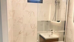 A modern bathroom with a glass shower enclosure, a vanity with a mirror, and a bathtub.