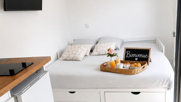 A modern bedroom with a bed, bedside table, and a wall-mounted TV displaying 'NETFLIX'.