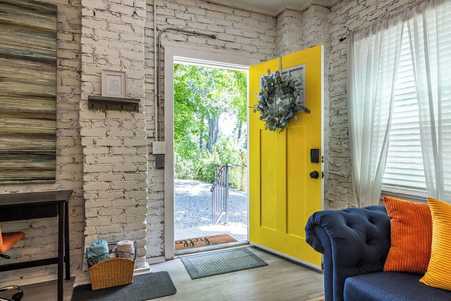A room with a brick wall, a yellow door, a blue sofa, and a fireplace.